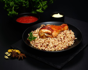 grilled chicken leg with wild rice on a black background