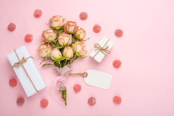 Bouquet with pink roses on a pink background with gifts, festive background, anniversary, wedding, Valentine's Day.Flat lay.top view, copy space