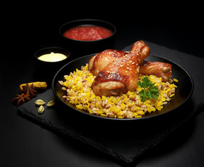 grilled chicken legs with sesame and rice on a black background.