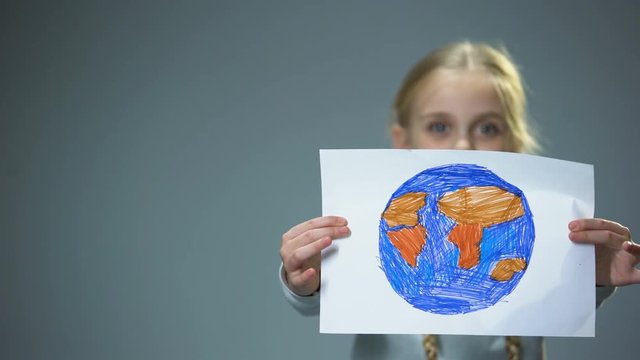 Smiling little child showing Earth picture into camera, global peace concept