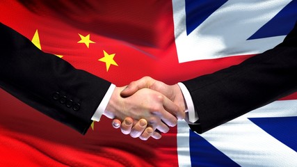 China and Great Britain handshake, international friendship, flag background