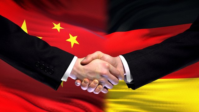 China and Germany handshake, international friendship relations, flag background