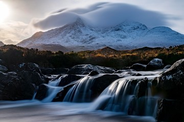 Scenic view of waterfall with snowcapped mountain in background