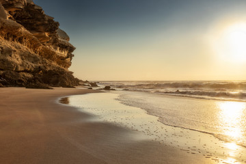 Beautiful sunset with cliff and rocky beach on deserted Namibe beach. Africa. Angola.
