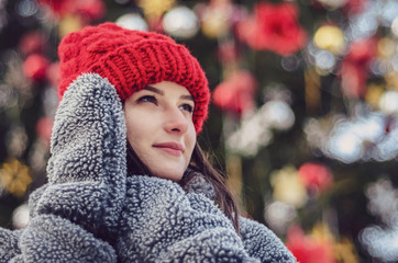 young, pretty model brunette poses for a photo in the winter near a Christmas tree in the middle of...