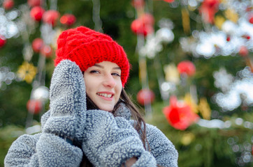 young, pretty model brunette poses for a photo in the winter near a Christmas tree in the middle of...
