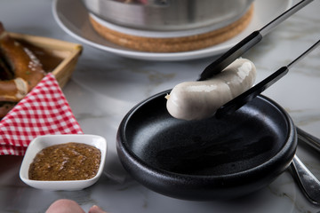 Mann isst Münchener Weißwurst mit Messer und Gabel, süßen Senf und Brezel und löst Wurst richtig aus Pelle