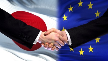 Japan and European Union handshake, international friendship, flag background