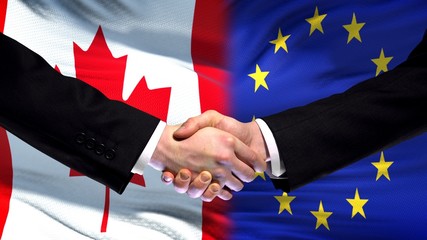 Canada and European Union handshake, international friendship, flag background