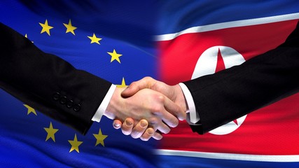 EU and North Korea handshake, international friendship relations flag background