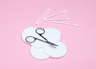 Hygienic manicure products on a pink pastel background. Cotton pads, cotton buds, nail scissors.