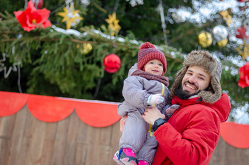 Handsome bearded young dad and his little cute little child daughter are having fun outdoor in winter. Enjoying spending time together. Family concept.
