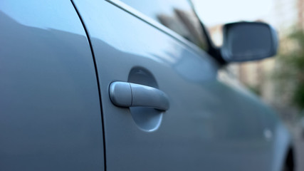 Modern car parked near building in background, door close up, security system