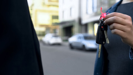 Happy woman receiving keys to new car from dealership manager, rental service