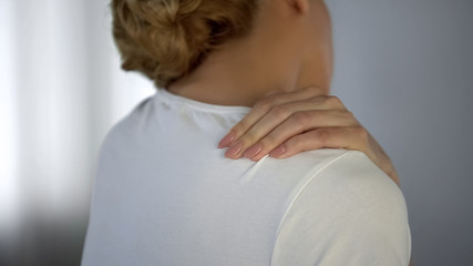 Woman massaging her painful shoulder, muscle ache after physical exercises