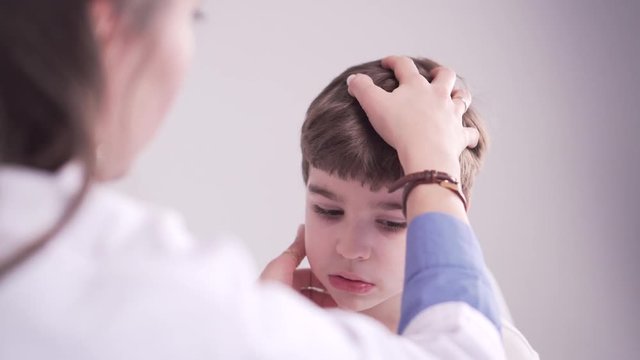 doctor is palpating lymph node on the neck of 7 years old boy, medical checkup
