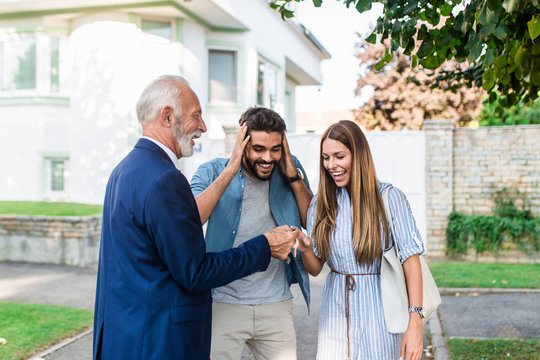 Young Couple Talking With Real Estate Agent And Buying A New House.