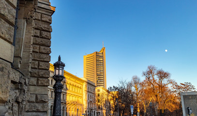 Ansicht vom City Hochhaus Leipzig mit historischer Laterne und Gebäuden im Vordergrund und blauen...