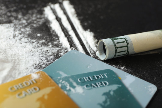 Cocaine, credit cards and rolled dollar banknote on black background