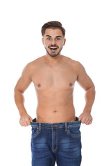 Fototapeta premium Fit man in oversized jeans on white background. Weight loss