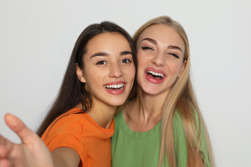 Young women laughing together against light background