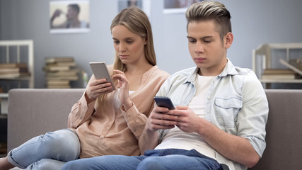 Teenage boyfriend and girlfriend shopping online on smartphones, addiction