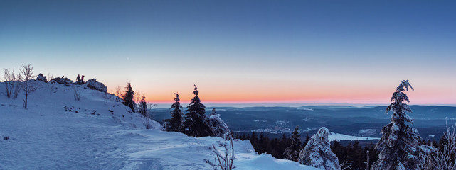 Mountain winter nature landscape with pine trees and a lot of snow and colorful sunset twilight sky. Harz Mountains National Park in Germany