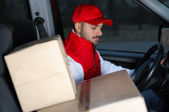 Deliveryman in uniform with parcels in car