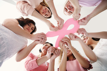 Women holding pink paper ribbon, bottom view. Breast cancer awareness concept