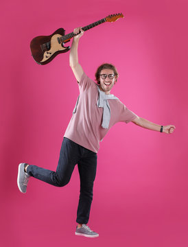 Young man with electric guitar on color background
