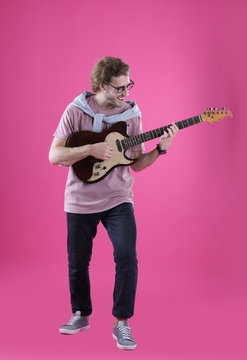 Young man playing electric guitar on color background