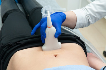 Closeup of a doctor using ultrasound equipment for screening a woman. Woman diagnosing in clinic
