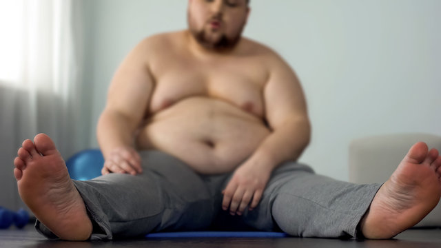 Overweight man resting after stretching exercises sitting on fitness mat
