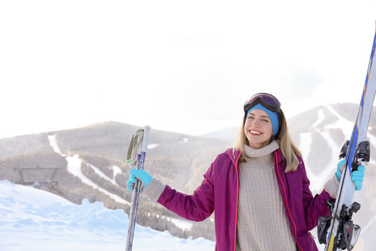 Happy young woman with ski equipment spending winter vacation in mountains