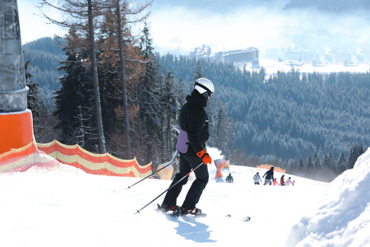 Man skiing on snowy hill in mountains. Winter vacation
