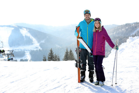 Happy couple with ski equipment spending winter vacation in mountains. Space for text
