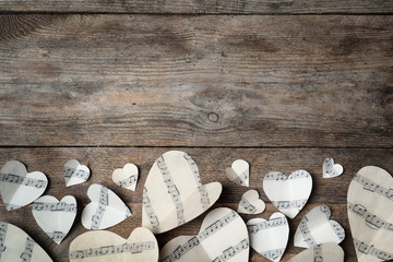 Paper hearts with music notes and space for text on wooden background, flat lay