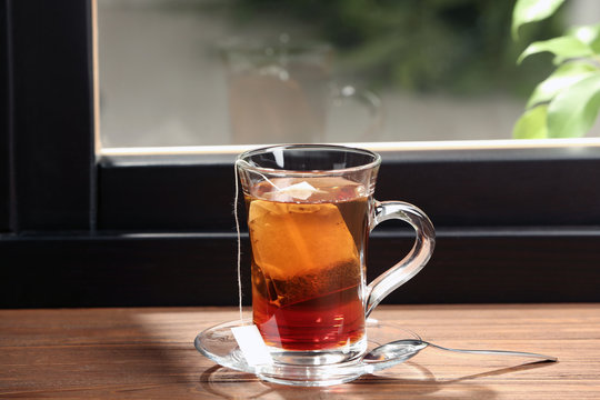 Glass cup of hot tea on wooden window sill