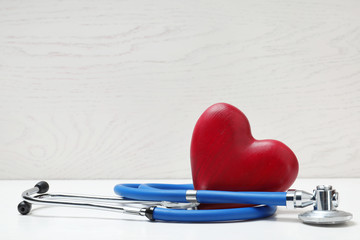 Medical stethoscope and wooden heart on table. Space for text