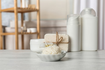 Bowl with Shea butter and other cosmetic products on table in bathroom. Space for text