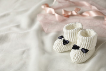Handmade baby booties on plaid. Space for text