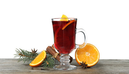 Composition with glass cup of mulled wine, cinnamon, orange and fir branch on table against white background