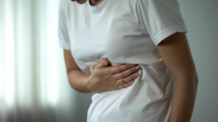 Female feeling stomachache, suffering from peptic ulcer, unhealthy eating result