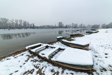 Danube island (Šodroš) near Novi Sad, Serbia. Colorful landscape with snowy trees, beautiful frozen river. A boats covered with snow or submerged.