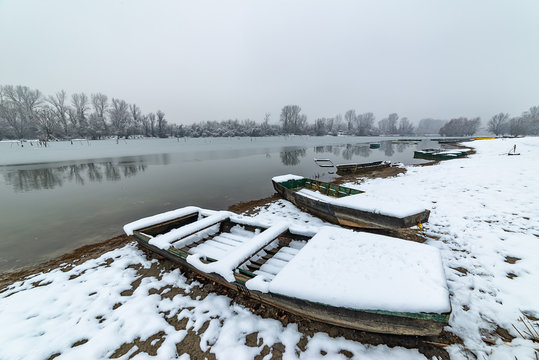 Danube island (&Scaron;odro&scaron;) near Novi Sad, Serbia. Colorful landscape with snowy trees, beautiful frozen river. A boats covered with snow or submerged.