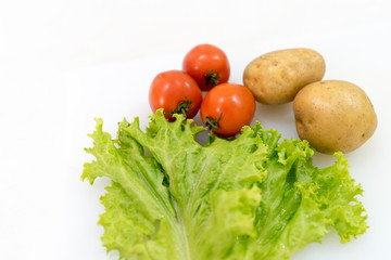 Tomato potato and lettuce isolated on white background with copy space. Healthy vegetables and herbs concept.