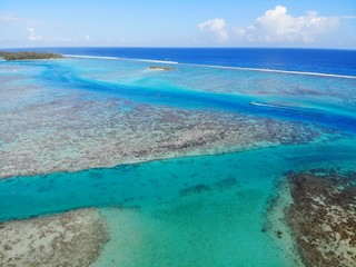 Obraz na płótnie Canvas Aerial view of shades of blue and coral reefs over the Moorea lagoon in French Polynesia, South Pacific