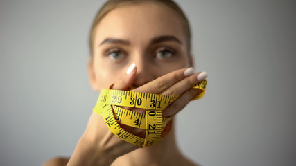 Fototapeta premium Anorexic girl closing mouth with tape, concept of severe food restriction