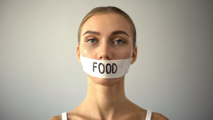 Thin model with taped mouth, concept of food restriction and anorexia, diet