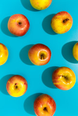 Apples with hard shadow on blue background, flat lay image.